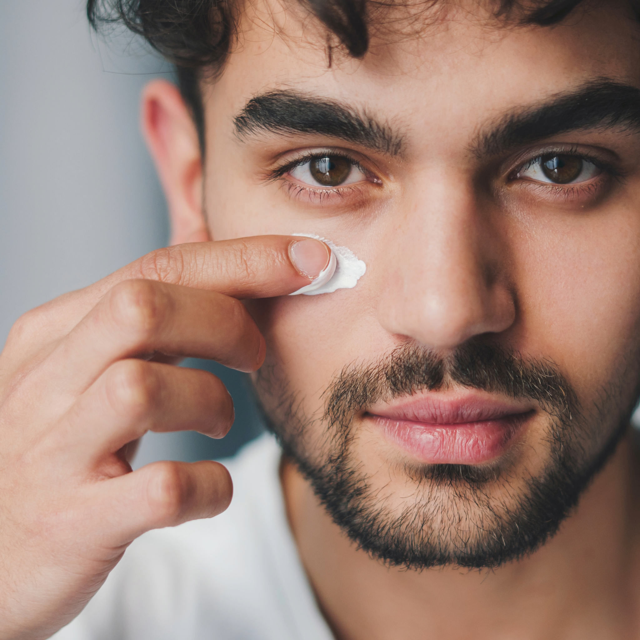 Moški nanaša polžjo kremo Heliroyal Plus pod oči — naravna nega kože za moške z vlažilnim in osvežilnim učinkom. Polžja krema Heliroyal plus.